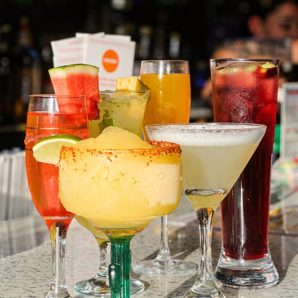 Assortment of colorful cocktails, including margaritas, sangria, and other mixed drinks, on a bar.