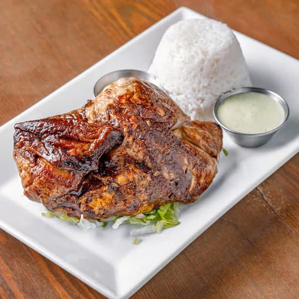 Peruvian-style grilled chicken with white rice and green sauce on a white plate.