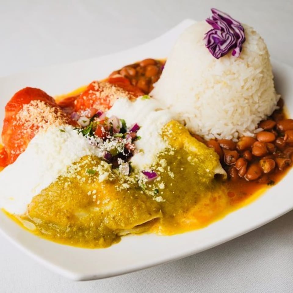 Peruvian/Mexican enchiladas with red and green sauce, rice, beans, and garnished with red cabbage.