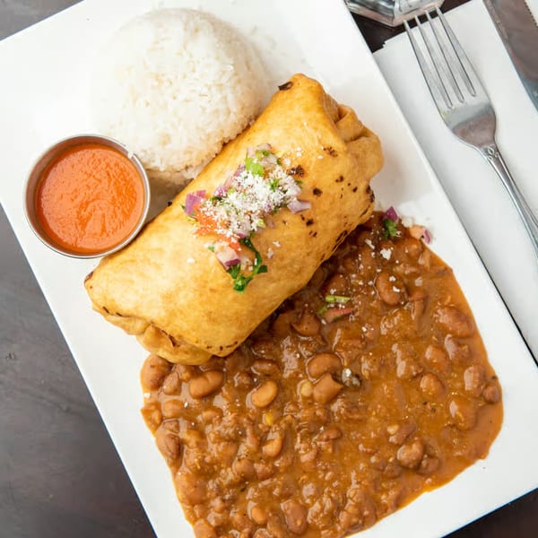 Golden-fried burrito topped with pico de gallo, served with rice, beans, and a side of red sauce.