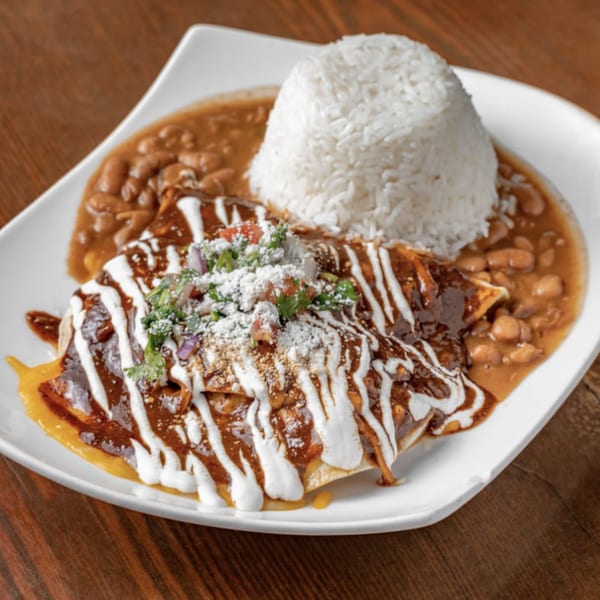 Peruvian/Mexican enchiladas with rice and beans, drizzled with sour cream and topped with cilantro.